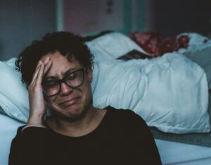 Personne pleurant à côté de son lit à cause du stress et de l'épuisement.