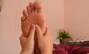 Mains de la praticienne en Ayurveda qui massent le pied d'un client allongé sur la table de massage. Soin ayurveda des pieds